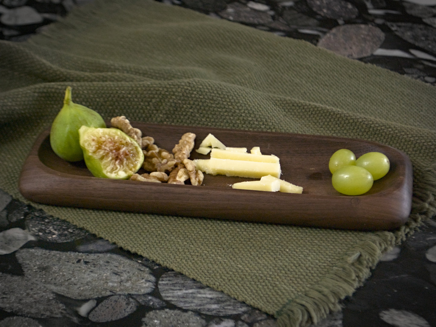 Wooden slim tray holding fruit, nuts and cheese